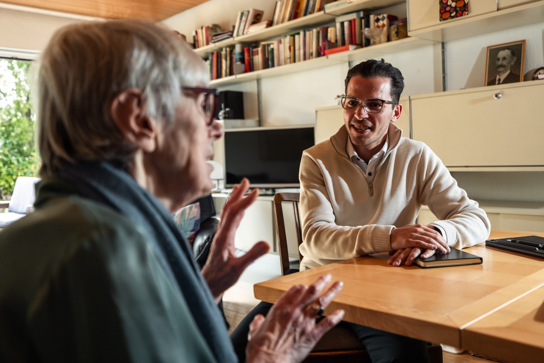Dominik Gissler von Nah & Da hört einer Seniorin beim Hausbesuch zu
